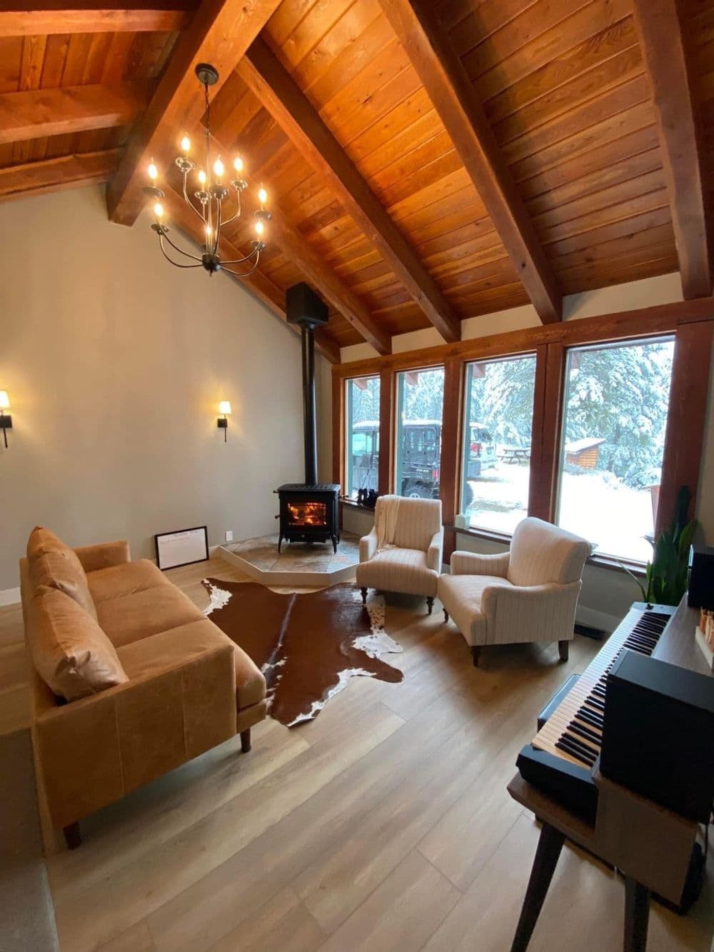 Cozy living room with wood beams, fireplace, and snowy outdoor view.