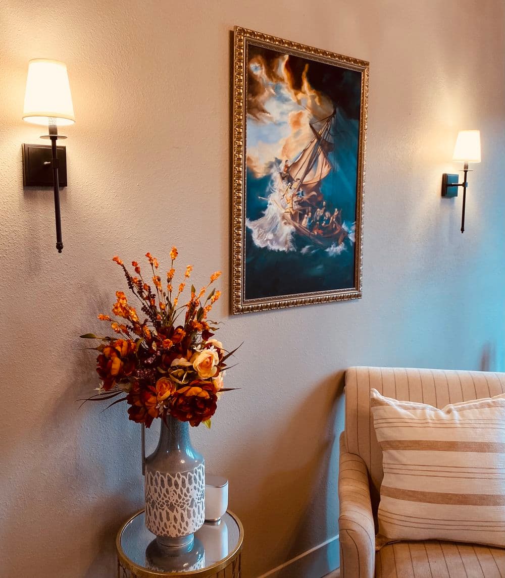 Cozy interior with a floral arrangement, sailboat painting, and stylish wall sconces.