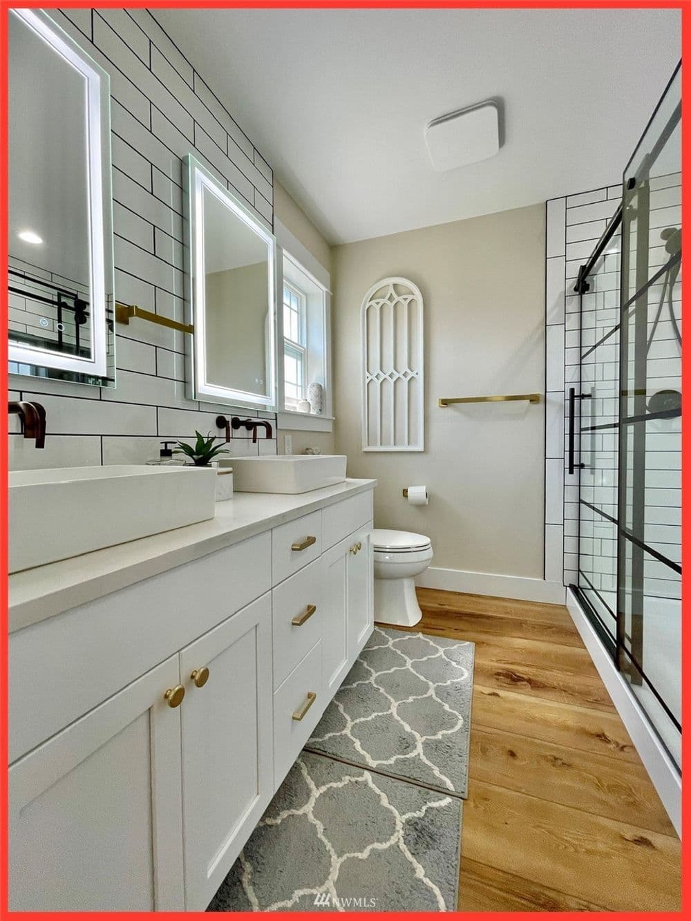 Modern bathroom with dual sinks, mirrors, glass shower, and stylish tile accents.