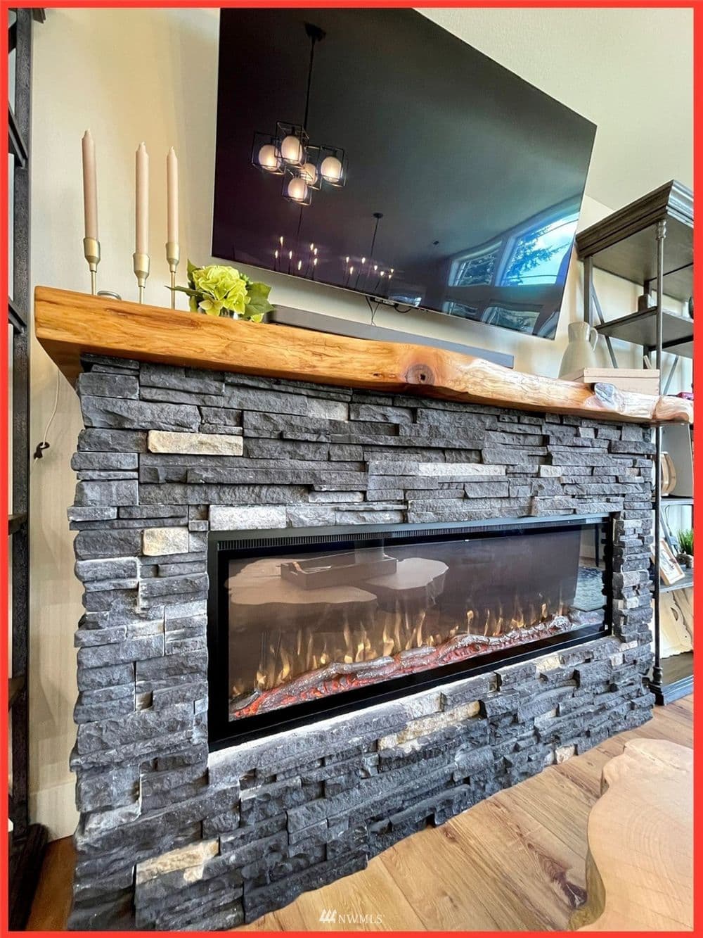Modern stone fireplace with a wooden mantel, flat-screen TV, and decorative candles.
